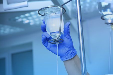 Рука врача поправлет капельницу